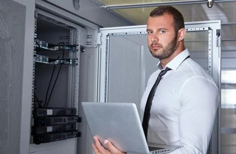 Man using laptop and working in modern server room Stock Photos