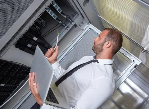 Man using laptop and working in modern server room Stock Photos
