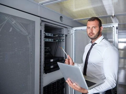 Man using laptop and working in modern server room Stock Photos