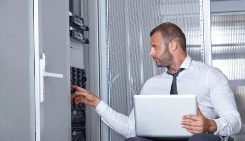 Man using laptop and working in modern server room Stock Photos