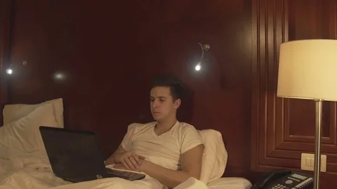 Man using laptop on the bed in home interior. Stock Footage 73984431