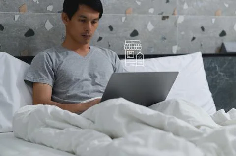 Man Using Laptop in Bed with Online Shopping Coupon Concept Stock Photos