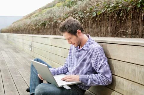 Man using a laptop on a boardwalk Stock Photos