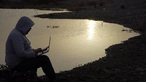 Man using laptop by coast lake. Adult man is holding laptop on his knees Stock Footage 238525779