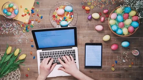 Man using laptop computer and digital tablet on table decorated with easter eggs Stock Footage 73938182