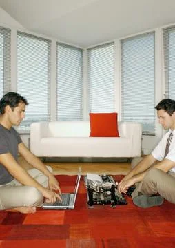 Man using laptop computer and second man using typewriter, side view Stock Photos