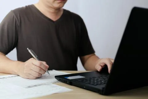 Man using laptop computer and taking notes in planning. which is payment on.. Stock Photos
