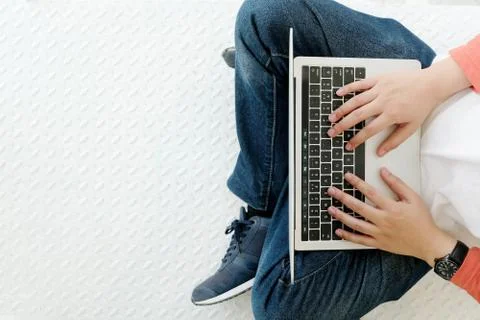 Man using laptop computer while sitting on white floor background with copy s Stock Photos