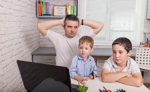 Man using laptop computer working at home. Stressed dad trying to work Fotos de archivo