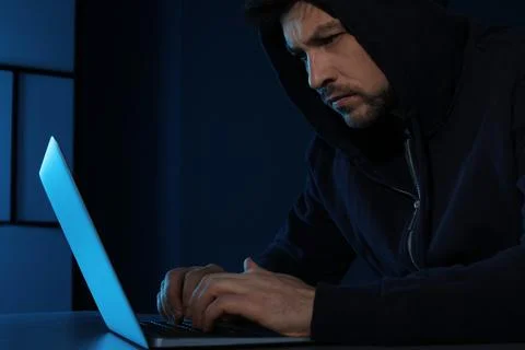 Man using laptop in dark room. Criminal offence Stock Photos