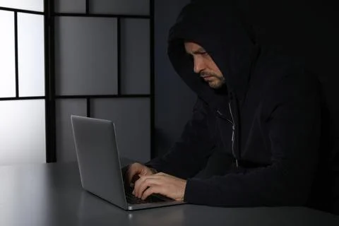 Man using laptop in dark room. Criminal offence Stock Photos