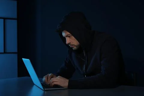 Man using laptop in dark room. Criminal offence Stock Photos