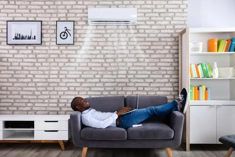Man Using Laptop Enjoying Cooling Under Air Conditioner Stock Photos