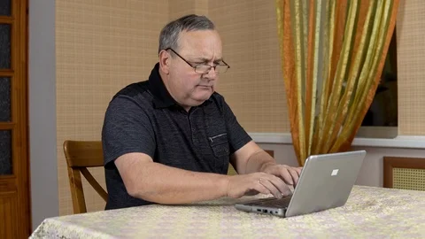 Man is using a laptop for the first time. The old man hardly uses a laptop Stock Footage 124667093