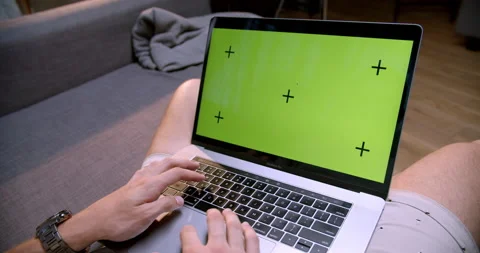 Man using laptop with green mock-up screen while sitting at the sofa Stock Footage 170634611