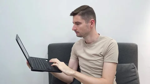 Man using a laptop on his lap, sitting on a sofa. Working from home concept Stock Footage 282610243