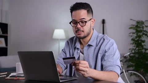 Man using laptop holding credit card for online shopping and payment at home Video stock 167942638