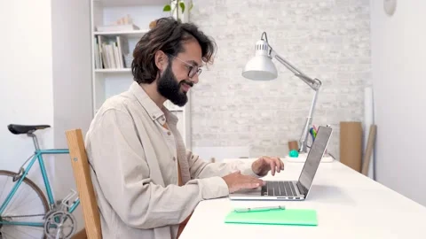 Man using laptop at home remote work in a small business. Handsome smiling male 스톡 동영상 223886958