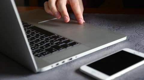 Man is using laptop. Mobile phone is lying next to the laptop on the table Stock Footage 61281799