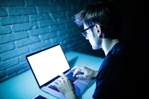 Man using laptop in the night with white screen. Young hacker work on laptop  Foto stock