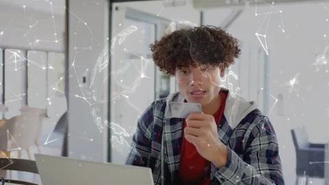 Man using laptop, raising phone and speaking into it, joining tech call as globe Stock Footage 333610049