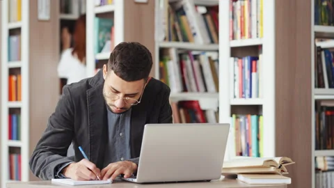 Man using laptop for research in library Stock Footage 169446593
