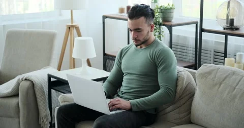 Man using laptop sitting on sofa at home Stock Footage 156543745