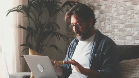 Man using laptop sitting on sofa in modern apartment. Caucasian male in eyeglass Stock Footage 171933431