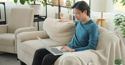 Man using laptop on sofa Stock Footage 145290477