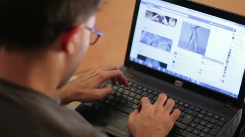 Man using a laptop to surf on facebook Stock Footage 12381466