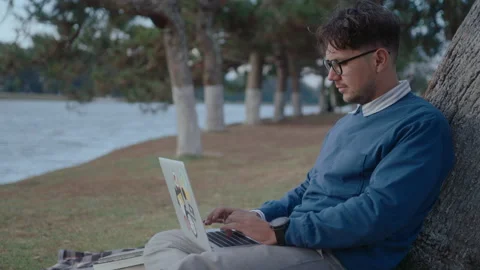 Man Using Laptop by Tree in Park Video stock 237057842