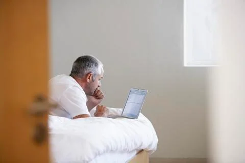 Man Using Laptop While Lying In Bed Stock Photos