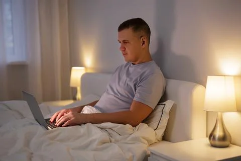 Man using laptop while lying in his bed at home 스톡 사진