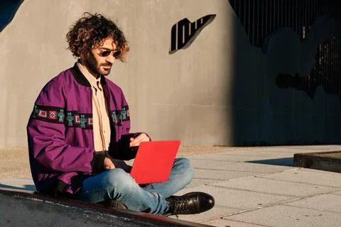 Man using a laptop while sitting outdoors. Stock Photos