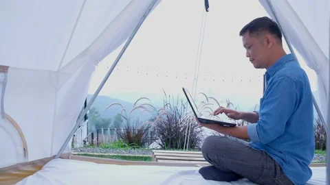 A man using a laptop works in tent. Effective communication. new normal. Stock Footage 136667031
