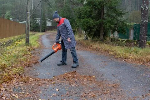 Man using leaf blower cleaning road in residential area Foto stock