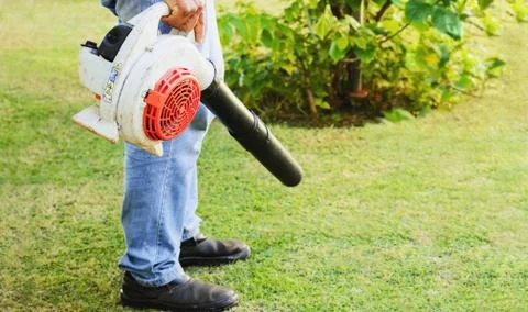 Man using a leaf blower on the lawn of the garden Stock-Fotos