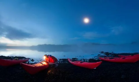 Man using light to examine canoes Foto stock