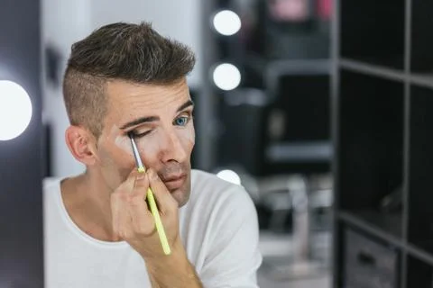 Man using makeup brush while applying eyeshadow on eyes. Stock Photos