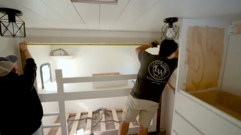 Man using a measuring tape to measure the top of a bunk bed frame with a mea Stock Footage 151518147