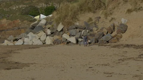 Man using a metal detector on a cornish beach Stock Footage 232251809