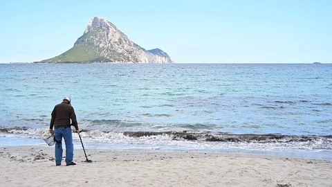 Man using metal detector searching treasures on beautiful beach Stock Footage 107845407
