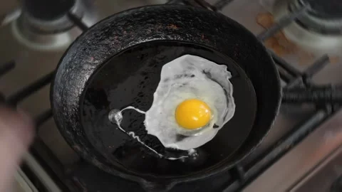 Man using metal knife breaks egg shell to fry egg in old griddle pan with oil. Stock-Footage 342920562