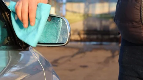 A man using microfiber wipes a side mirrors in a car. Car care concept. Video stock 124125847