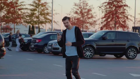 Man using mobile app to unlock rental car in urban parking lot, surrounded by Stock Footage 315529522