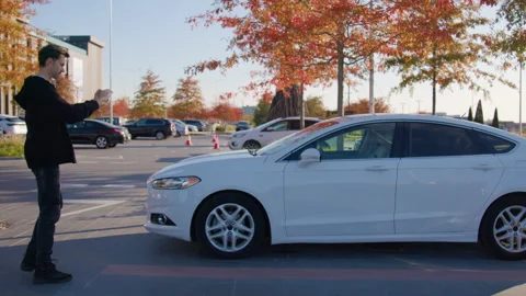 Man using mobile app to unlock rental car in urban setting, showcasing modern Stock Footage 315532746