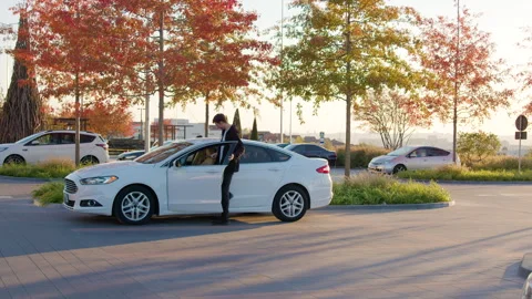 Man using mobile app to unlock rental car in urban setting, surrounded by trees Video stock 316836291