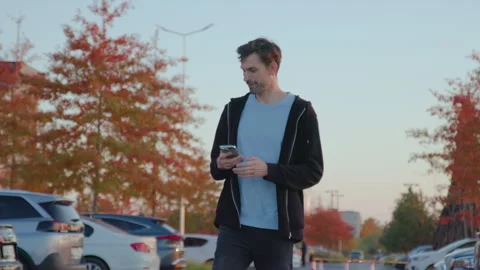 Man using mobile app to unlock rental car in urban environment, surrounded by Stock Footage 317701748