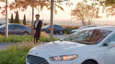 Man using mobile application to unlock rental car in urban setting surrounded by Stock Footage 315528816