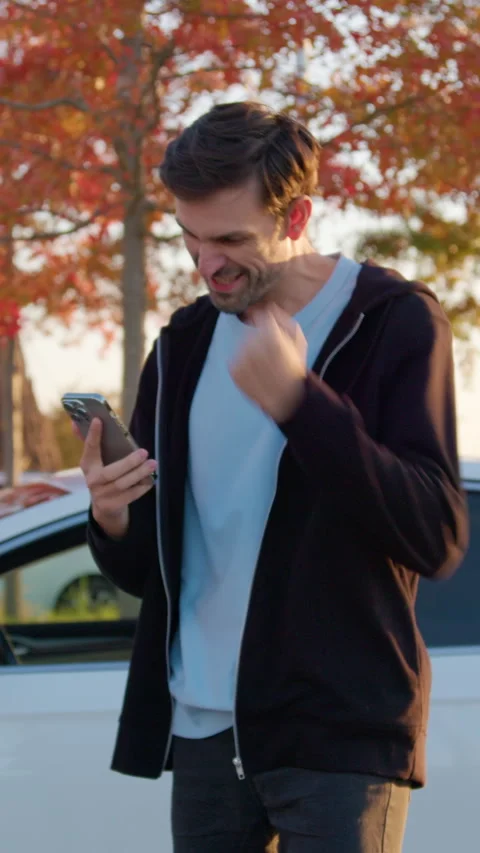 Man using mobile application to unlock rental car in urban setting, surrounded Stock Footage 318474253